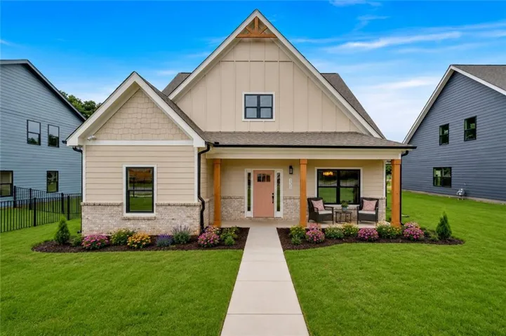 Craftsman-style home featuring a covered front porch with wood columns, a light pink entry door, and dark-framed windows
