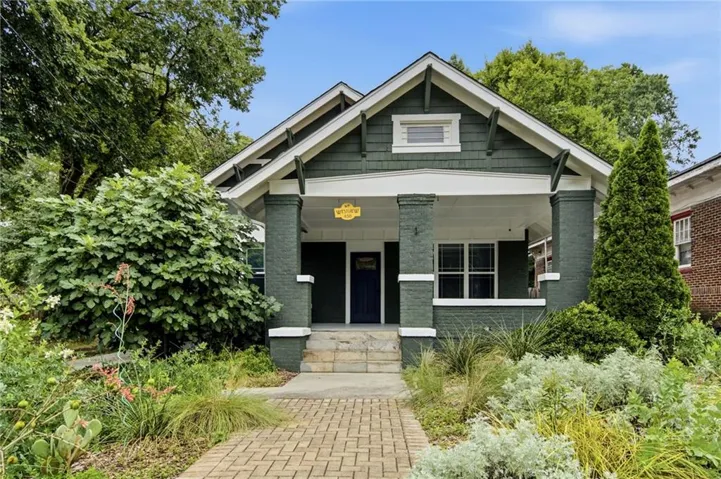 1930's Craftsman Bungalow featuring a covered porch, brick paver walkway, and mature landscaping
