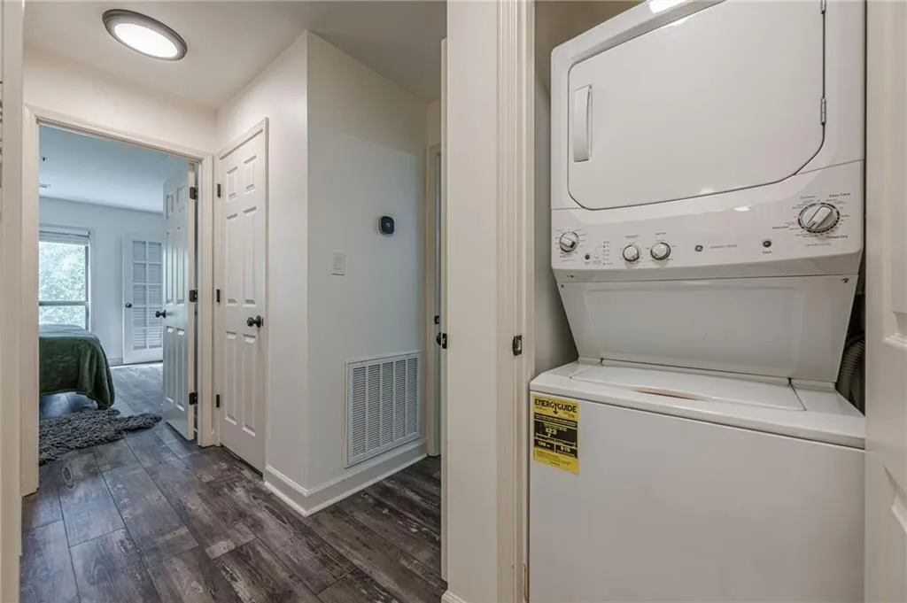 Washroom featuring stacked washer / dryer and dark wood-style floors