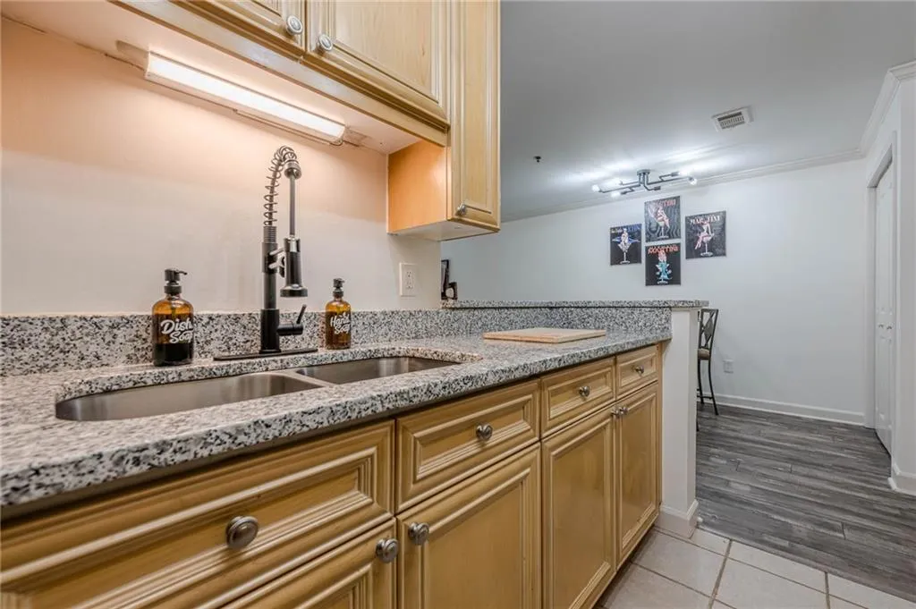Kitchen with light stone countertops, light tile patterned flooring, and ornamental molding