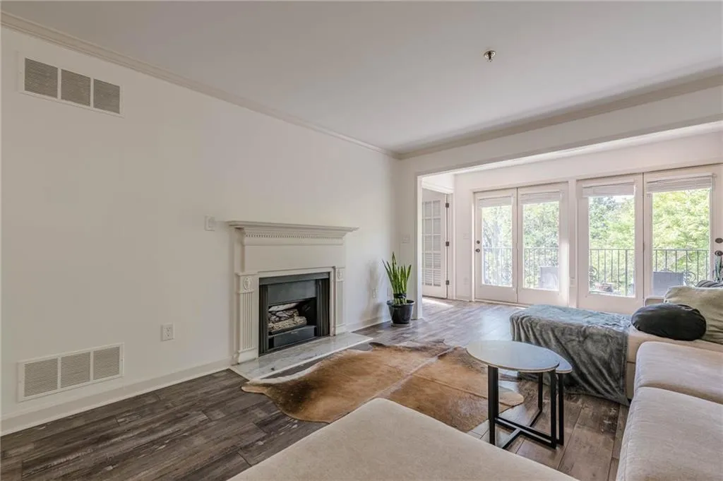 Living area with ornamental molding, dark wood finished floors, and a fireplace with raised hearth