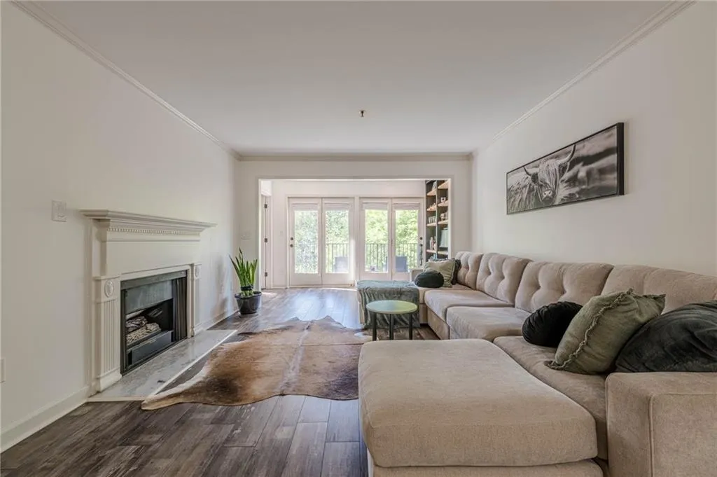 Living area featuring dark wood-style floors, ornamental molding, and a high end fireplace