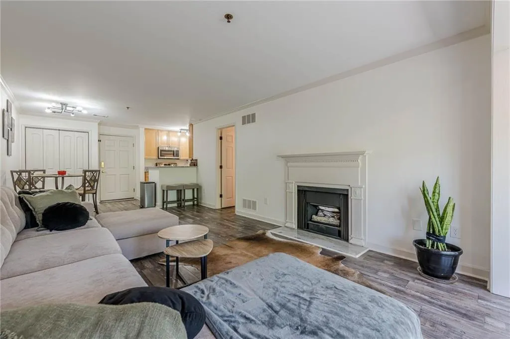 Living room with ornamental molding, wood finished floors, and a fireplace with raised hearth