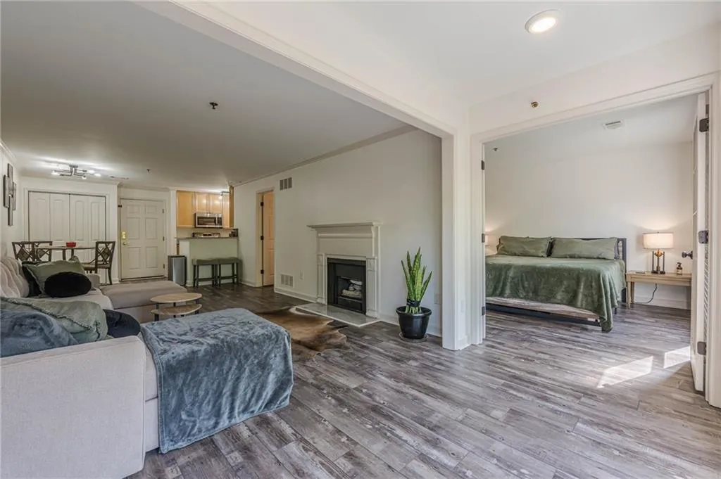 Living area with wood finished floors, a fireplace with raised hearth, and ornamental molding