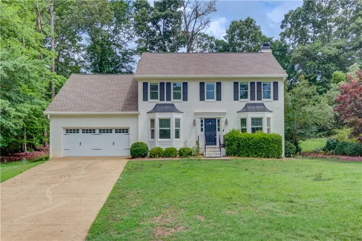 Two-story residence featuring a two-car garage, bay windows with metal accent roofs, and a concrete driveway