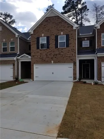 Brick exterior with white trim, black shutters, and white garage doors