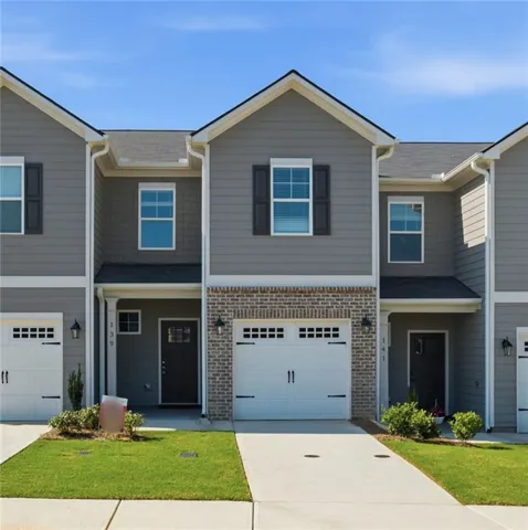 Modern townhome community featuring classic architectural details with gabled rooflines, contrasting black shutters, and cream trim accents