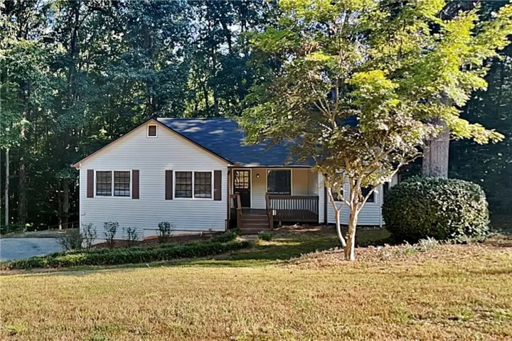 Light-colored siding exterior with dark shutters, covered front porch, and a gable roofline