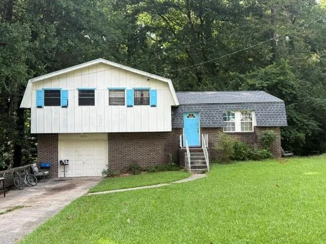 Split-level exterior featuring brick siding, white upper siding, and a light blue entry door
