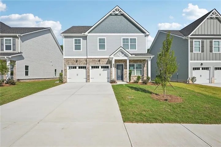Craftsman-style home featuring a garage, driveway, a front lawn, and stone siding