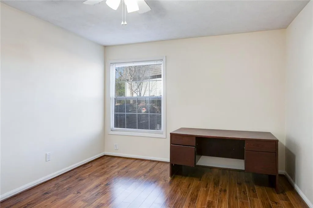 Empty room featuring dark wood-type flooring and ceiling fan