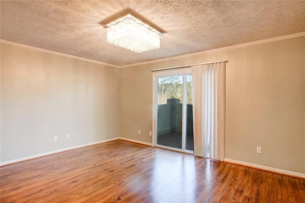 Spare room with wood-type flooring, a textured ceiling, a chandelier, and ornamental molding