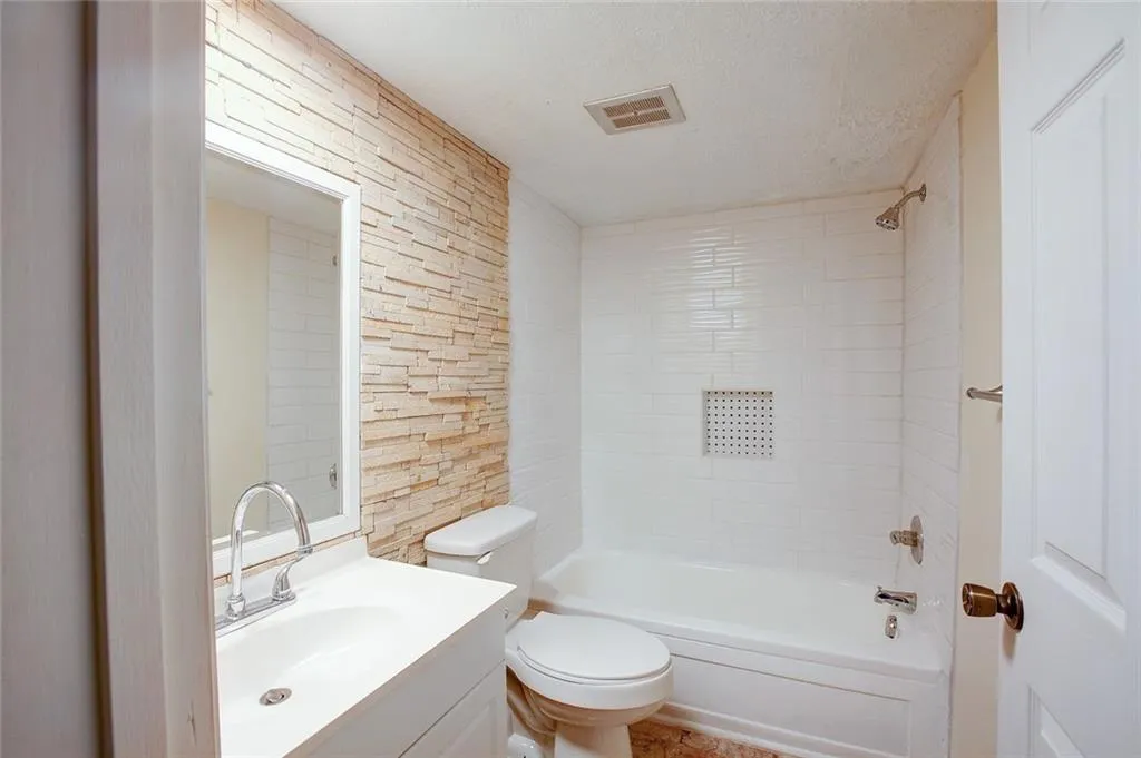 Full bathroom with a textured ceiling, vanity, toilet, and shower / tub combination
