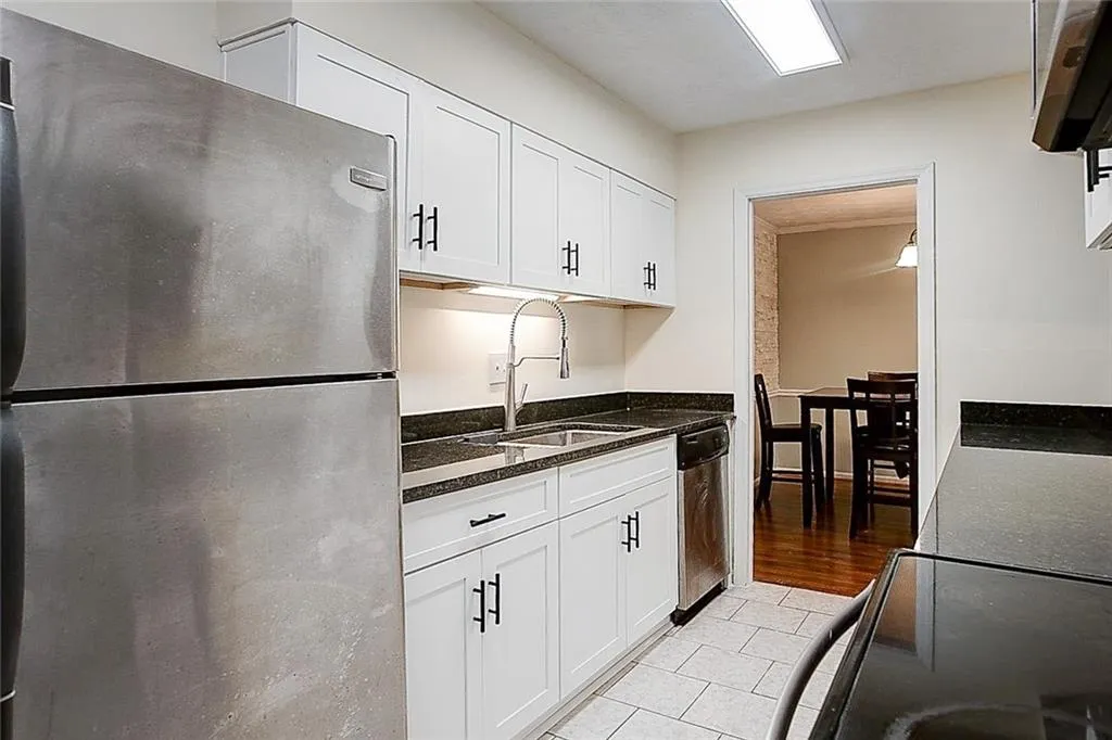 Kitchen with white cabinets, sink, stainless steel appliances, and light tile floors