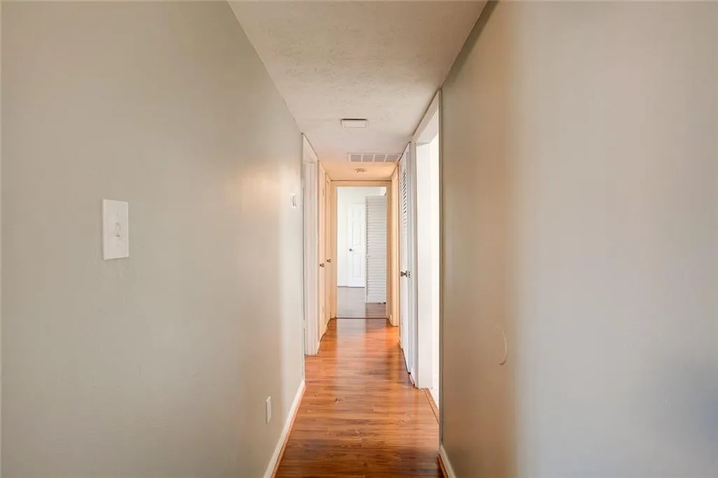 Corridor with a textured ceiling and hardwood / wood-style floors