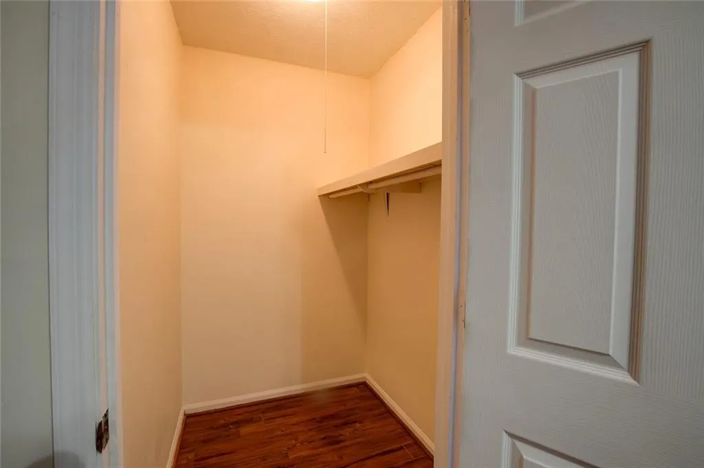 Walk in closet with dark wood-type flooring