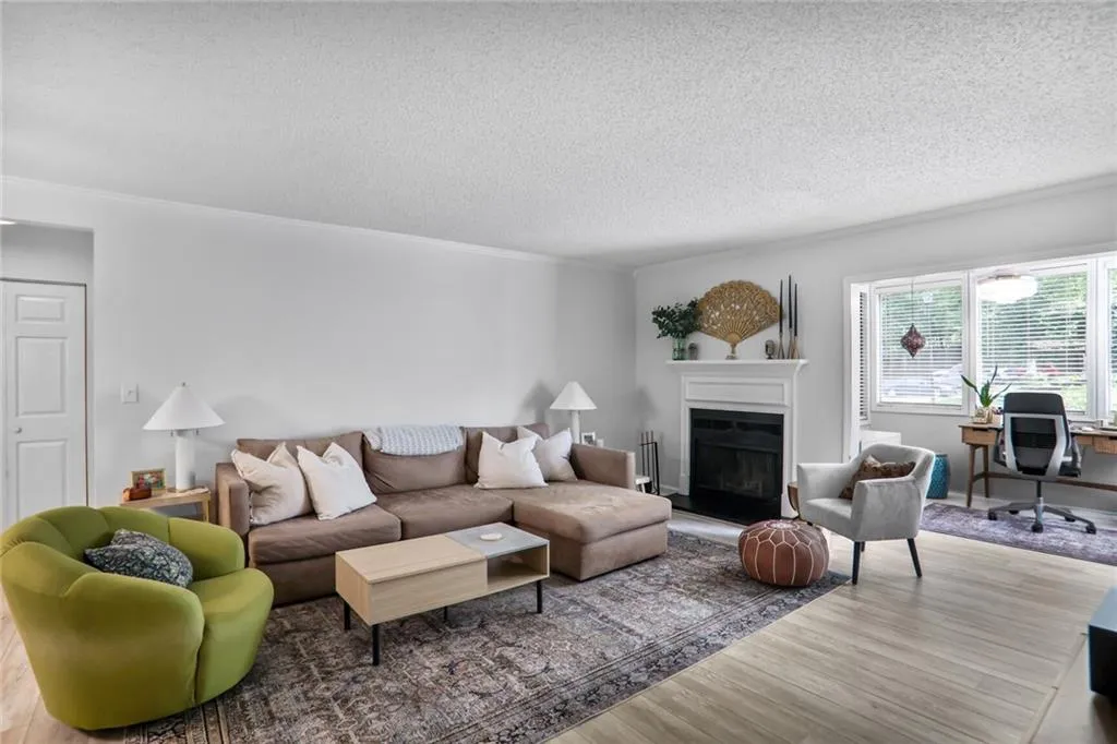 Living room featuring new flooring,a glass covered fireplace, and crown molding