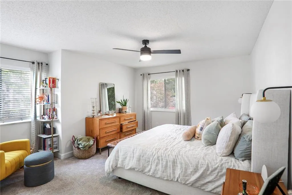 Carpeted bedroom with a ceiling fan, a textured ceiling, and baseboards
