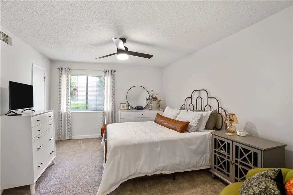 Bedroom with light carpet, a textured ceiling, and ceiling fan