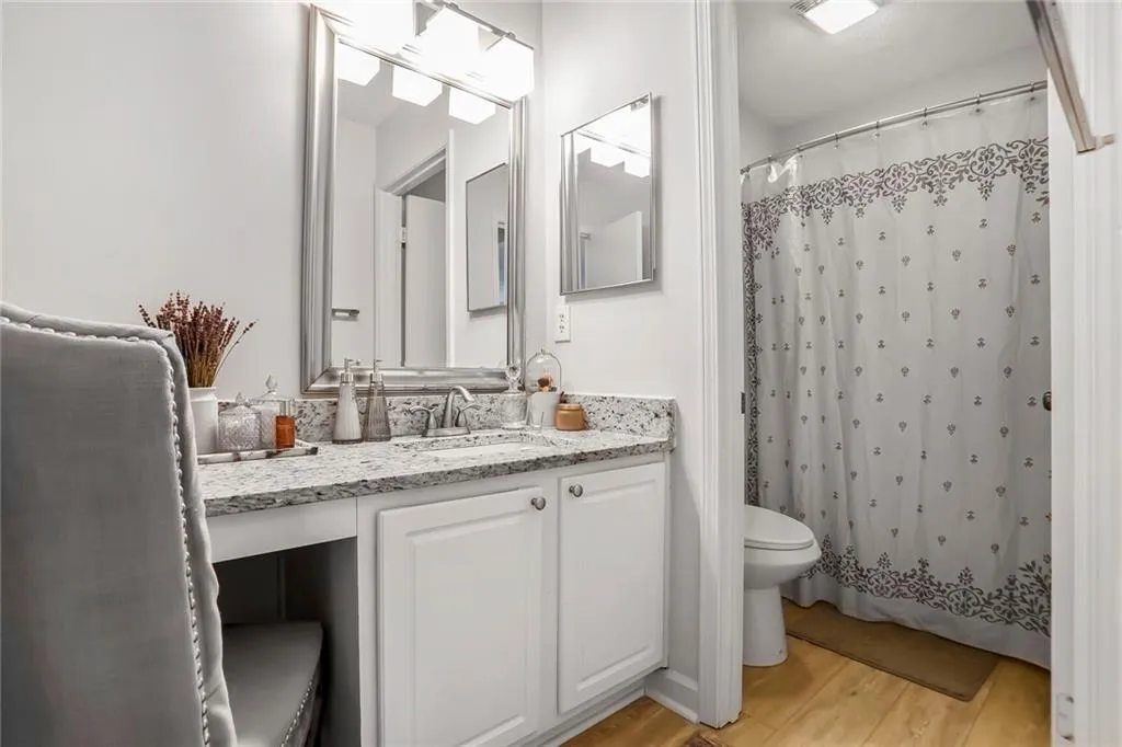 Full bath with new shower/tub enclosure, new flooring, vanity, and curtained shower