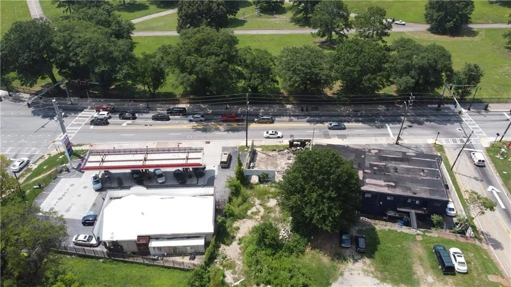 Aerial perspective of a commercial property featuring a gas station with multiple pumps and a flat-roofed building, alongside a separate two-story structure with a dark exterior