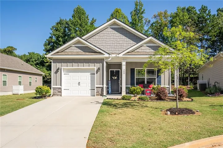 Exterior featuring mixed siding, a covered front porch, an attached garage, a paved driveway, and established landscaping