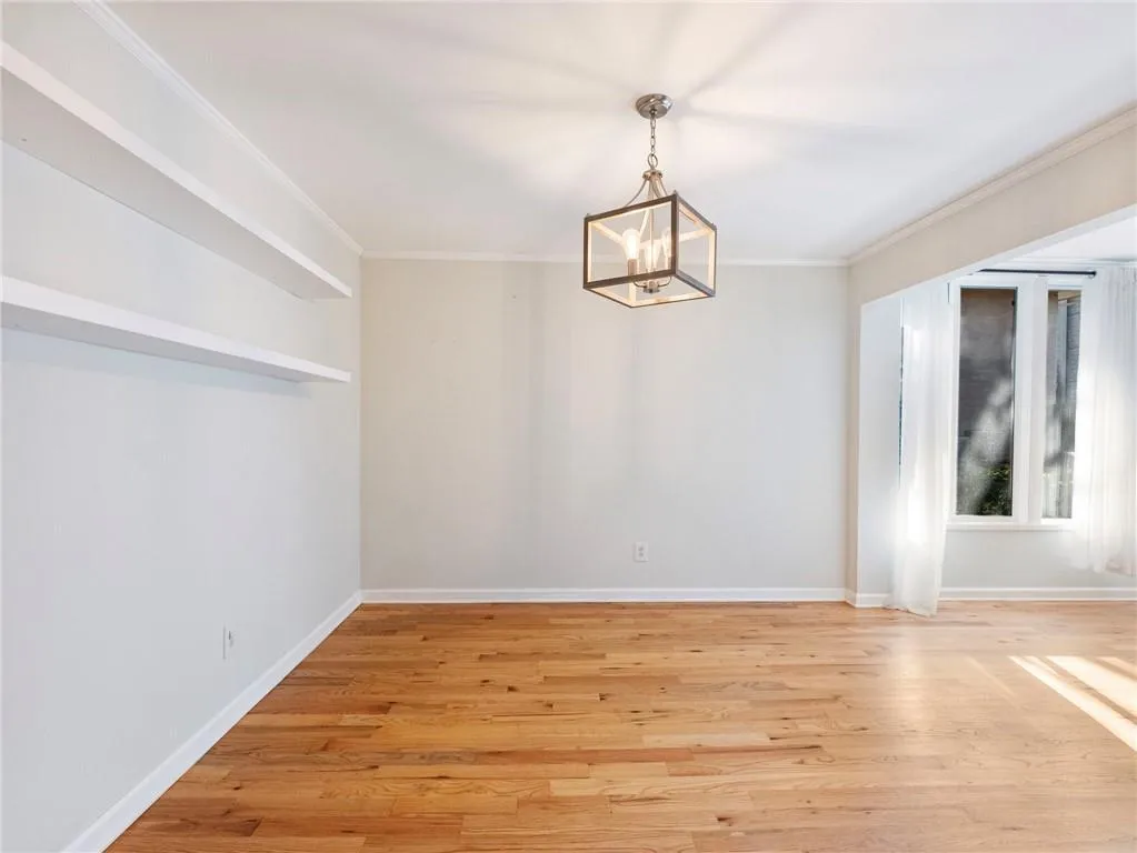 Unfurnished dining area featuring light wood-style floors, crown molding, and a chandelier