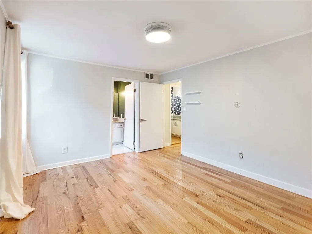 Unfurnished room with crown molding and light wood finished floors