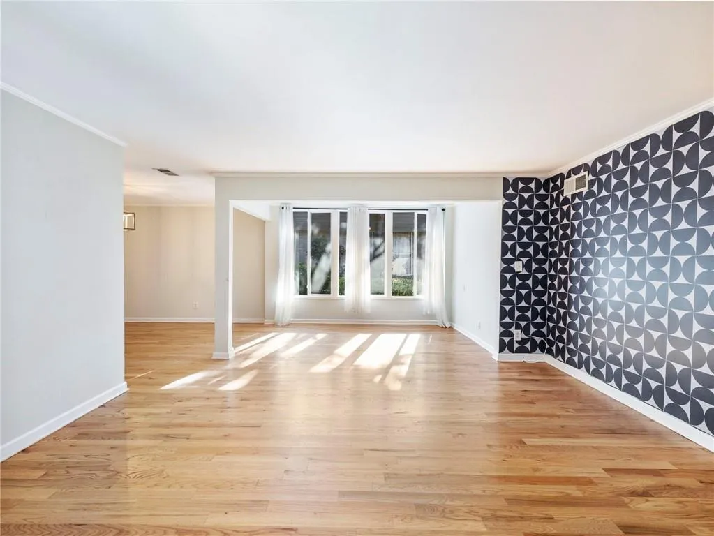 Unfurnished room with light wood-type flooring and ornamental molding