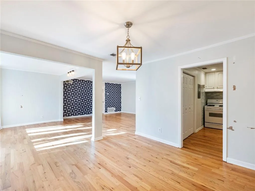 Unfurnished living room featuring ornamental molding, light wood-type flooring, and a chandelier