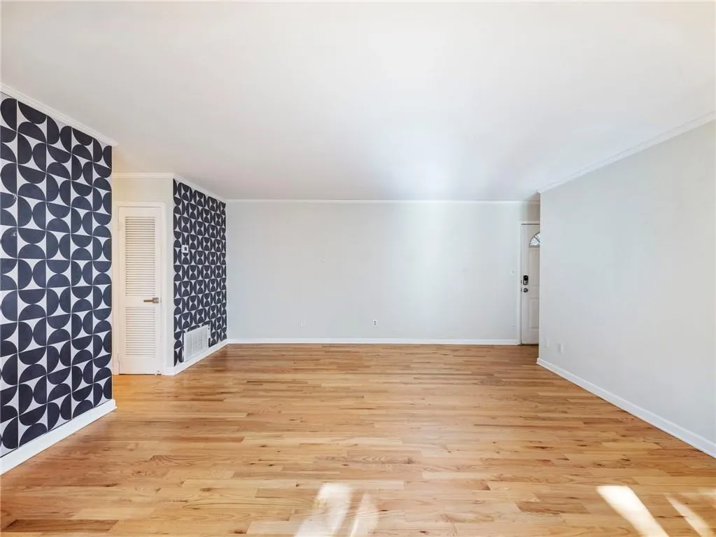 Unfurnished living room featuring light wood-style flooring and ornamental molding