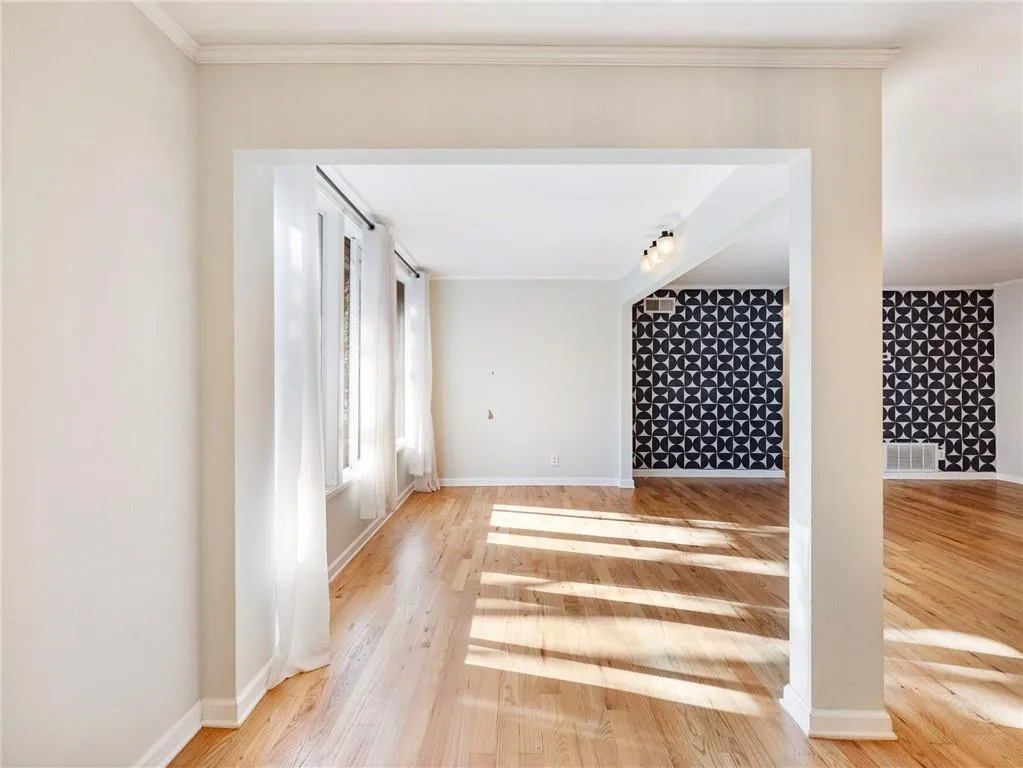 Unfurnished living room featuring light wood-style flooring and ornamental molding