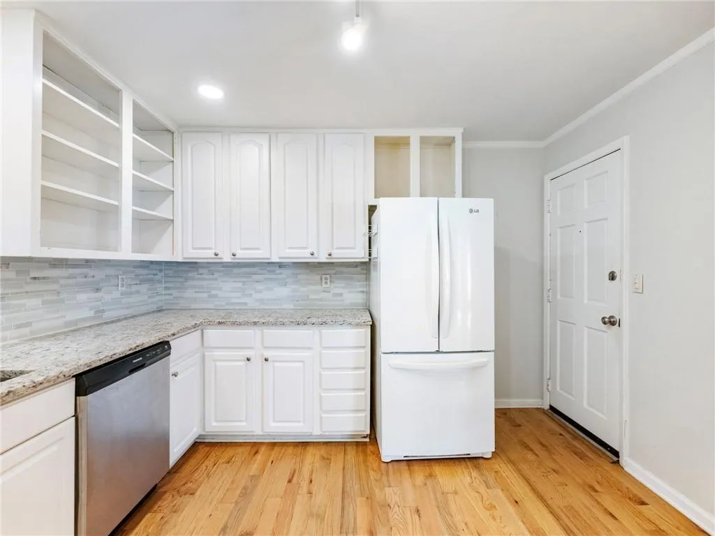 Kitchen featuring open shelves, white cabinetry, dishwasher, and freestanding refrigerator