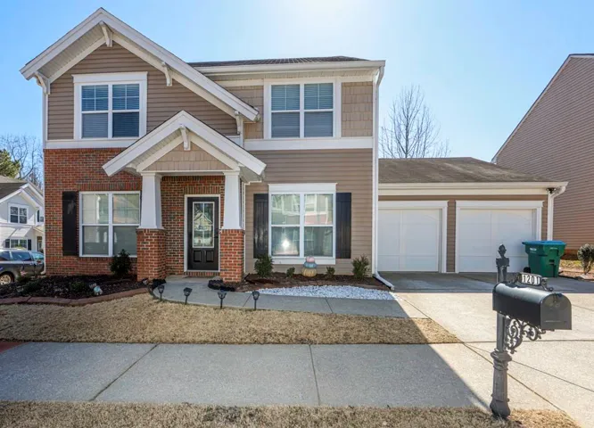 View of front of property with an attached garage, concrete driveway, and brick siding