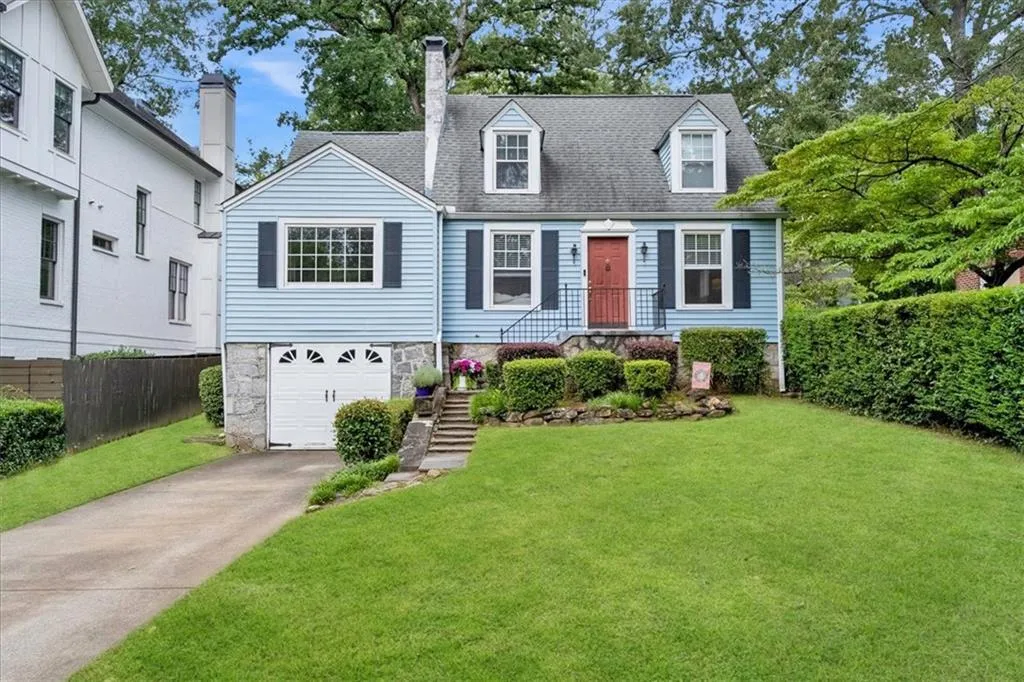 Cape cod-style house featuring driveway, a shingled roof, an attached garage, and a chimney