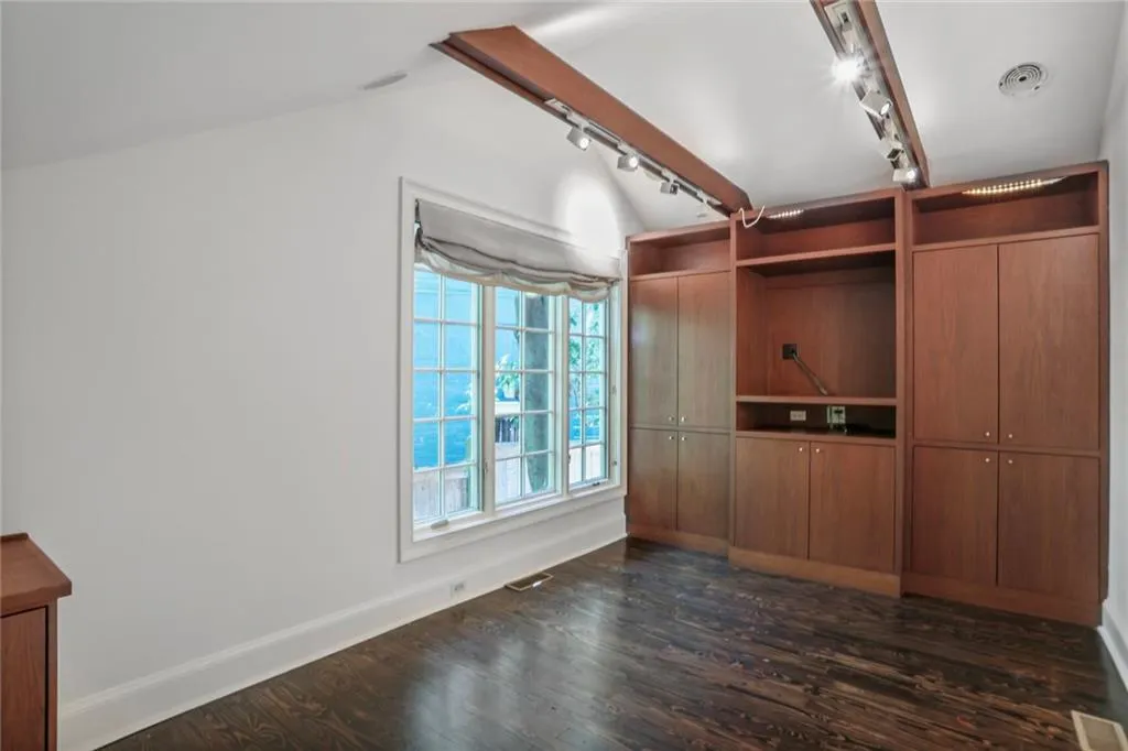 Unfurnished living room featuring dark wood finished floors, lofted ceiling, and track lighting