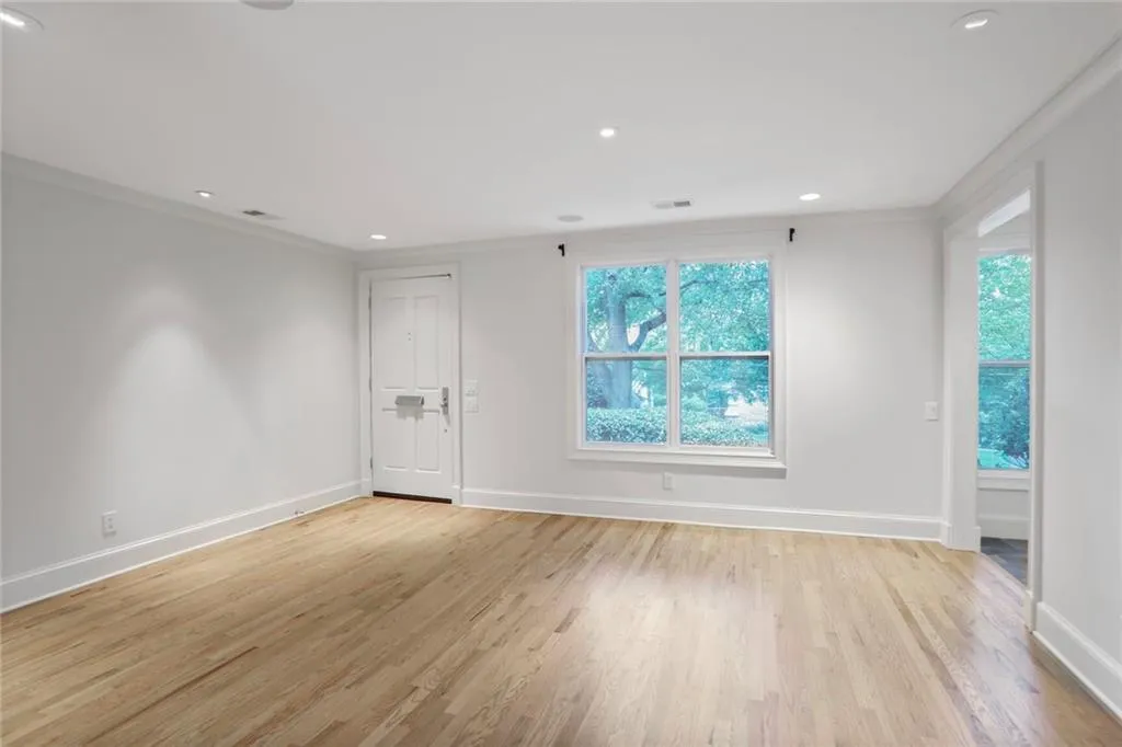 Empty room featuring plenty of natural light, light wood-style flooring, crown molding, and recessed lighting