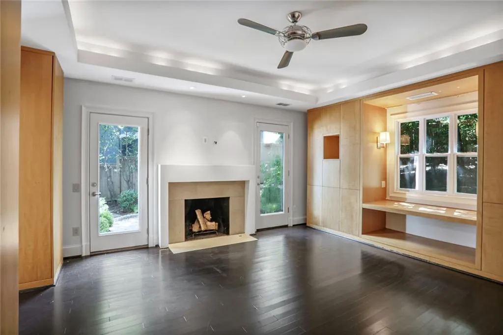 Unfurnished living room with a ceiling fan, a high end fireplace, and dark wood-type flooring