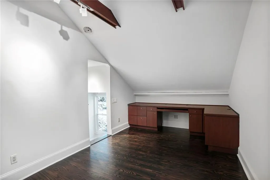 Additional living space featuring lofted ceiling, dark wood-style floors, and an office area