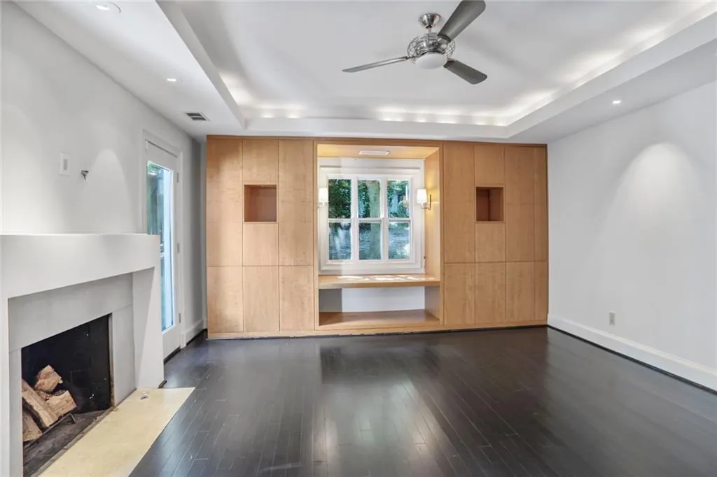 Unfurnished living room with a raised ceiling, a ceiling fan, a fireplace, dark wood finished floors, and recessed lighting