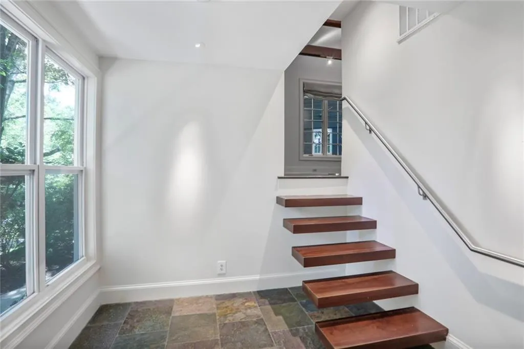 Staircase with baseboards and stone finish floors