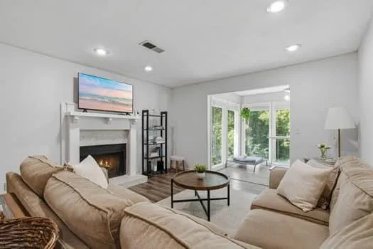Living area featuring a fireplace with a white mantel, recessed lighting, and wood-finish flooring