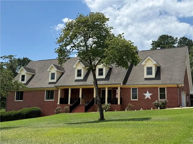 Brick exterior featuring a covered porch, dormer windows, and a multi-level roofline
