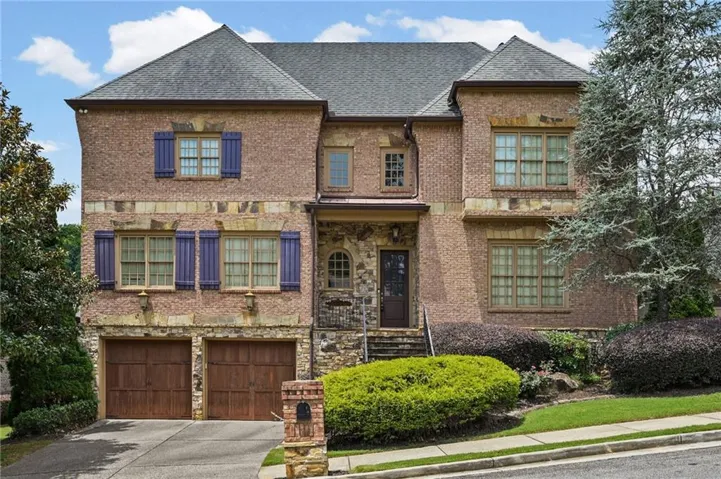 Brick and stone facade residence featuring a multi-gabled roofline and a prominent arched entryway