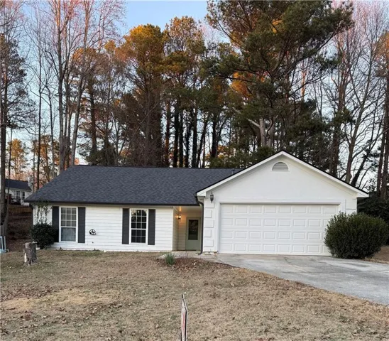 Ranch-style house featuring driveway, a garage, roof with shingles, and a front lawn