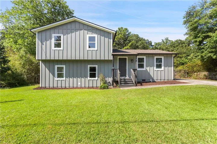 Modern farmhouse-style residence featuring board-and-batten exterior siding in neutral tones, complemented by a pitched roof design
