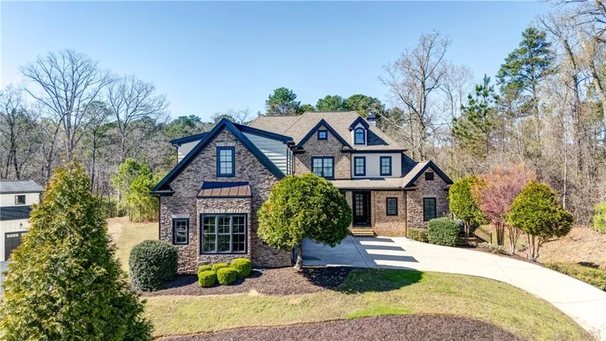 Stone and siding exterior with dark trim accents, multi-pane windows, dormer windows, and a detached two-story structure