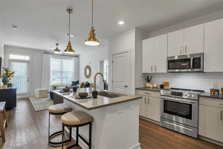 Kitchen featuring appliances with stainless steel finishes, pendant lighting, dark wood-style flooring, an island with sink, and recessed lighting