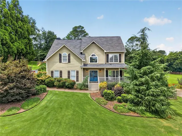 Traditional-style home featuring a covered front porch, gabled roofline, and dormer windows