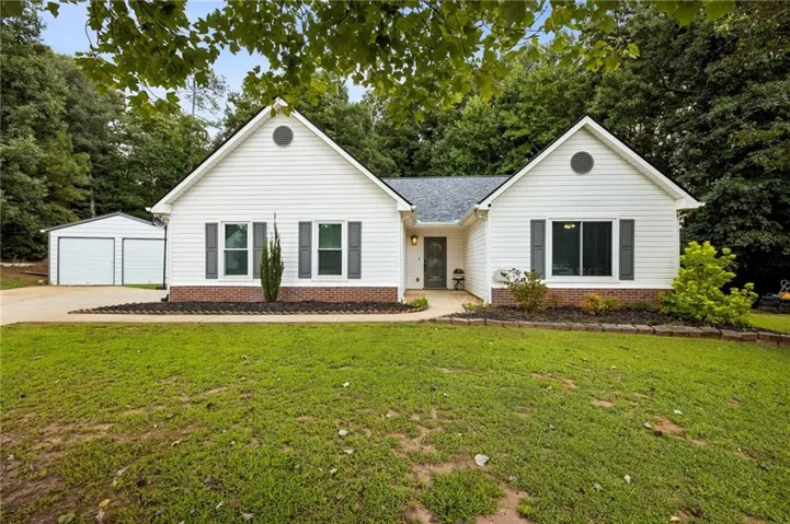 Modern ranch-style home featuring clean white siding, a two-car garage, and a gabled roofline with architectural shutters
